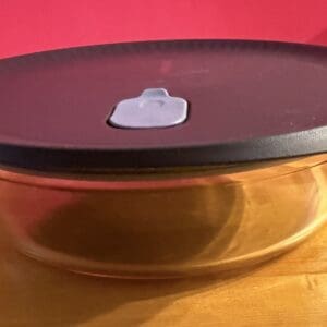 A round brown plate with a white sticky note on top against a red background.