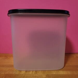 A translucent plastic container with a black lid on a wooden surface.