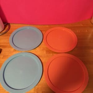 Four round silicone mats in blue and orange on a wooden surface.