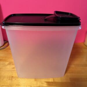 Clear plastic container with a black lid on a wooden surface.