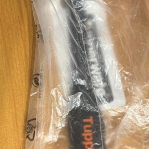 Two packaged kitchen utensils, a spatula and a brush, on a wooden table.