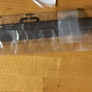 Black electronic device on wooden surface wrapped in plastic.