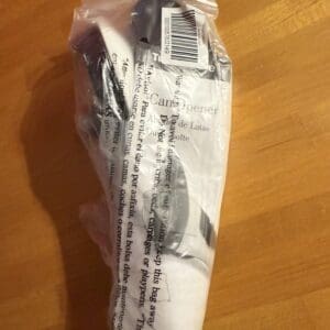 Plastic-wrapped item with barcode and text on a wooden surface.