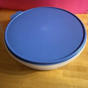 Blue plastic lid on a white bowl on a wooden surface.