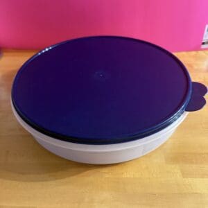 Round container with a purple lid on a wooden surface.
