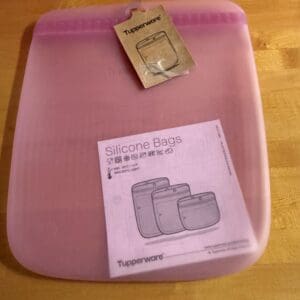 Pink silicone storage bags set with packaging on wooden surface.
