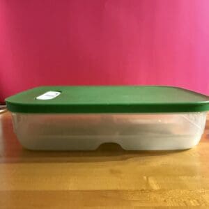 Rectangular container with a green lid on a wooden surface.