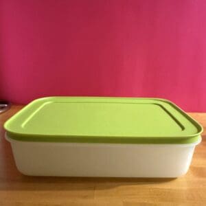 Rectangular white storage container with a green lid on a wooden surface.