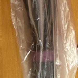 A black umbrella with a curved handle wrapped in plastic on a wooden surface.