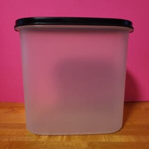 A translucent plastic container with a black lid on a wooden surface.