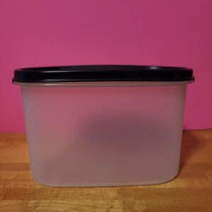 A translucent plastic container with a black lid on a wooden surface.