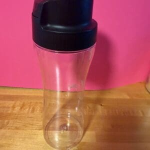 Clear plastic water bottle with a black lid on wooden surface.