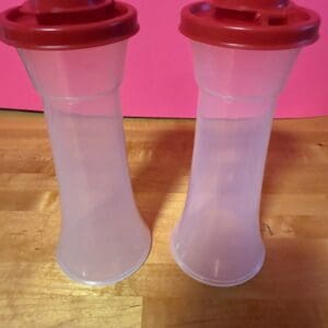Two translucent plastic containers with red lids on a wooden surface.