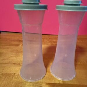 Two translucent plastic containers with gray lids on a wooden surface.